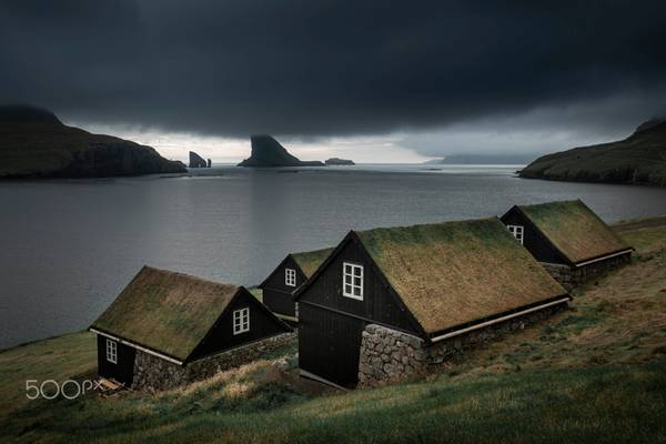 Houses with grass roofs in front of Drangarnier rocks, Faroe Islands