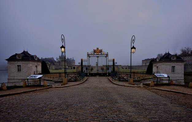 Front gate of Château de Chantilly on a misty morning
