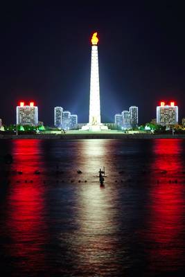 Pyongyang by night. Juche Tower across Taedong river