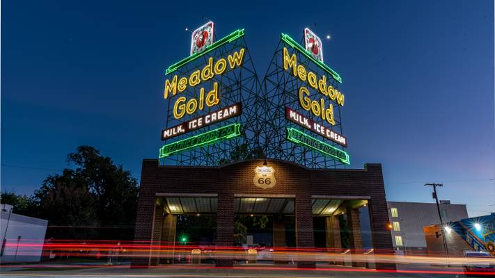 Blue hour photo of the Iconic Meadow Gold Neon sign restored along Rt. 66 with car light trails