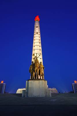 Pyongyang at the blue hour. Juche Tower & bronze sculpture of worker, intellectual & peasant