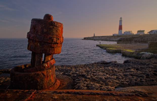 Rusty capstan overlooking a lone fisherman