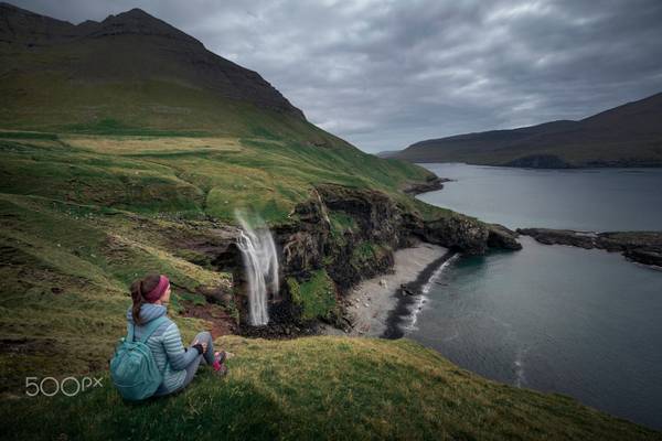 Female hiker at Skarðsáfossur waterfall of Vagar, Faroe Islands